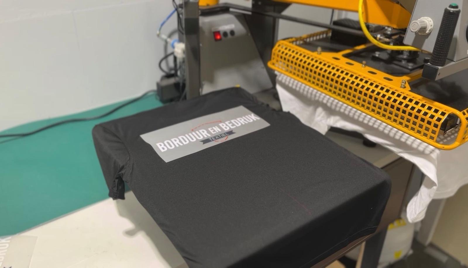 Bedrukt shirt met ons logo onder de heatpress in het eigen atelier in Zelhem
